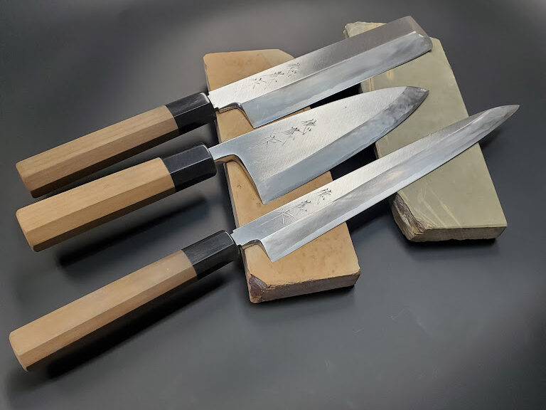 3 Japanese japanese knives, resting on two natural Japanese whetstones 